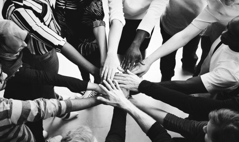 A diverse group of people joining hands in a circle, representing the inclusive and multilingual family lawyer services provided by DV Law in Toronto and the GTA.