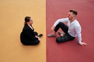 Man and woman sitting apart on divided yellow and red ground, symbolizing legal separation vs divorce in Ontario.